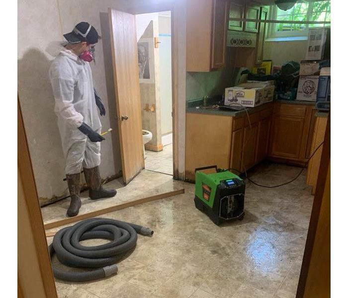 SERVPRO employee standing in PPE in sewage flooded home