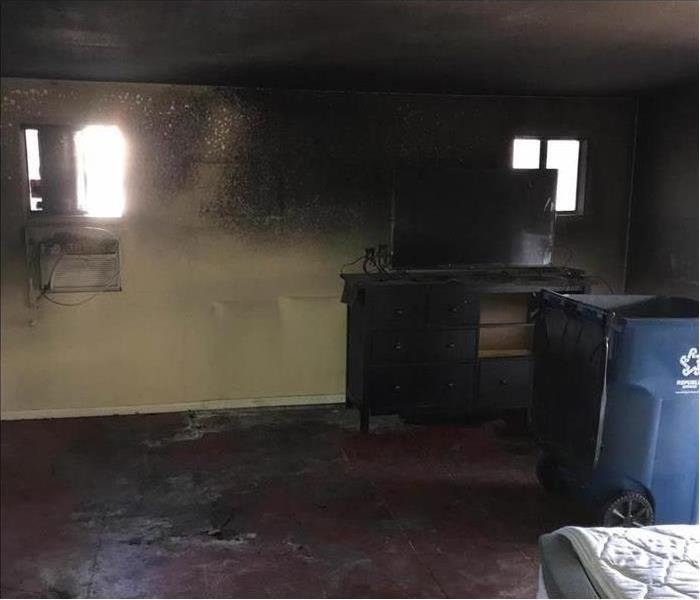 Walls of a room with soot damage, wooden furniture with tv with smoke damage