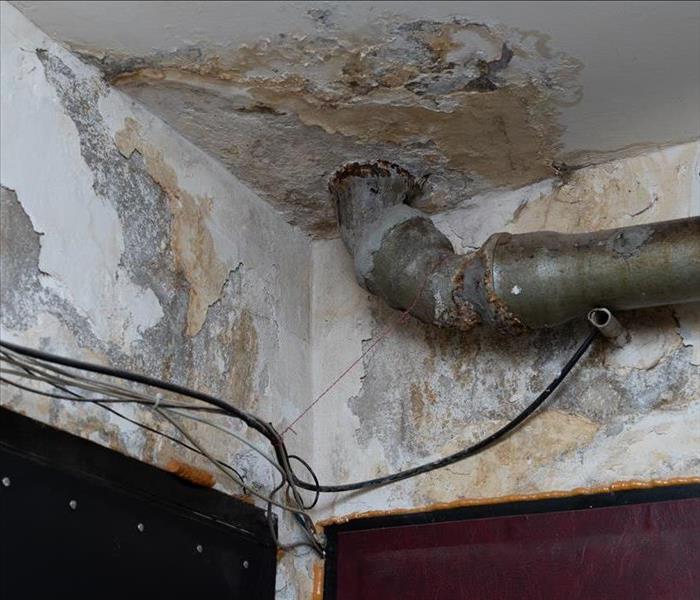 Old water leak on ceiling building, water damaged plaster and pipe, utility services problem